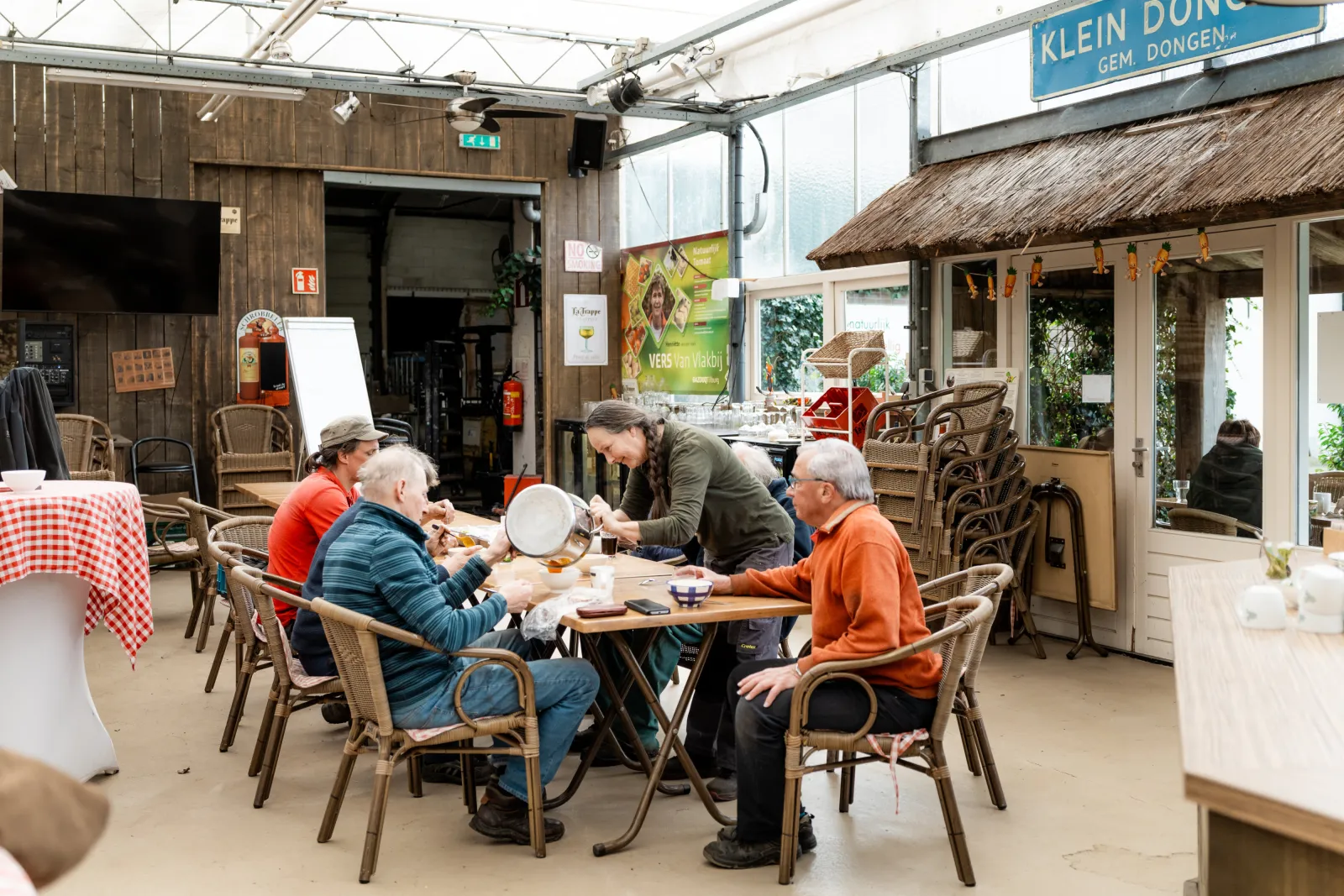 Een groepje mensen zit aan tafel in "Klein Dongen". 