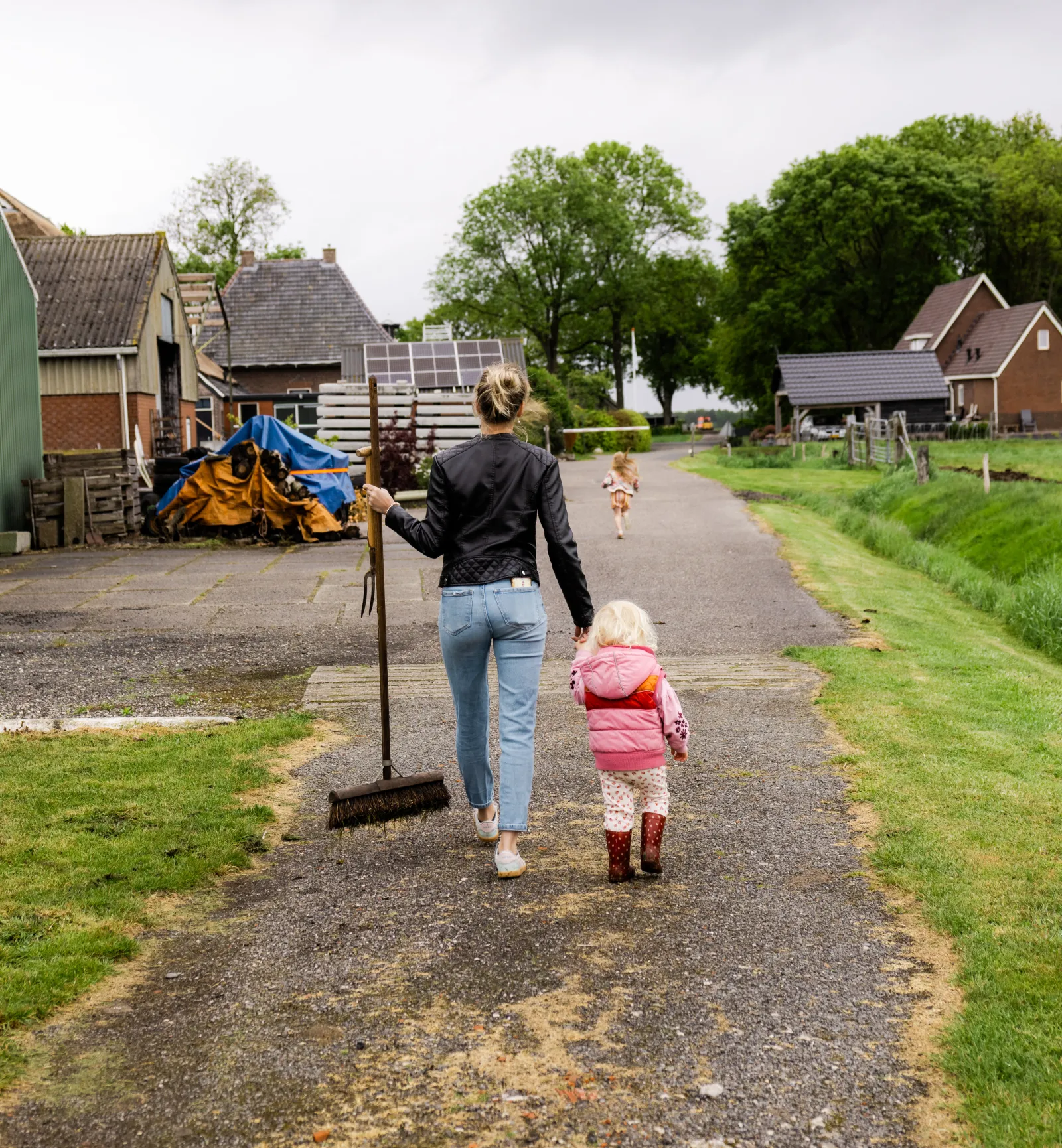 Mariet en haar dochter lopen over het erf, haar andere dochter rent verderop.