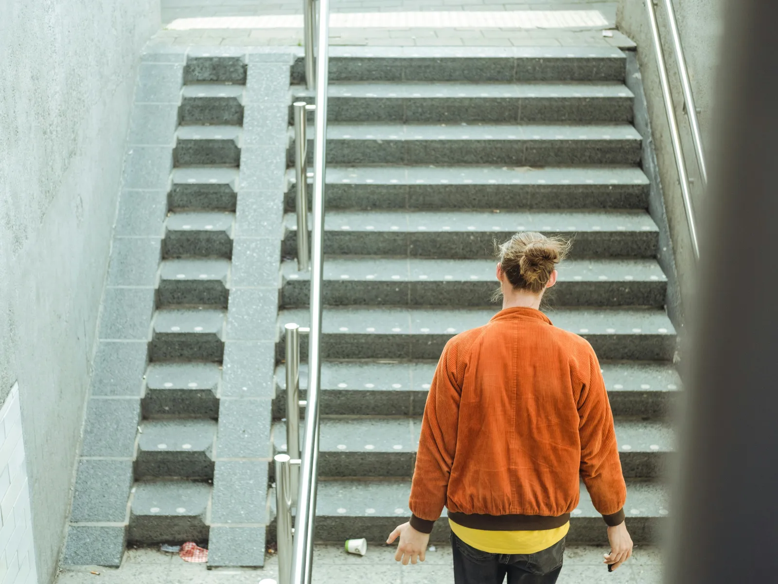 Iemand loopt een trap af in een Nederlands treinstation. 