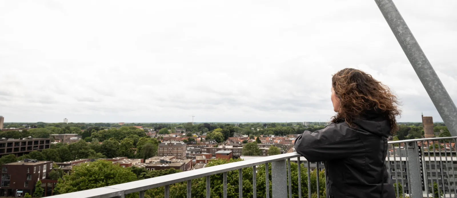 Een persoon kijkt op de top van de Kempentoren in het Spoorpark uit over Tilburg.