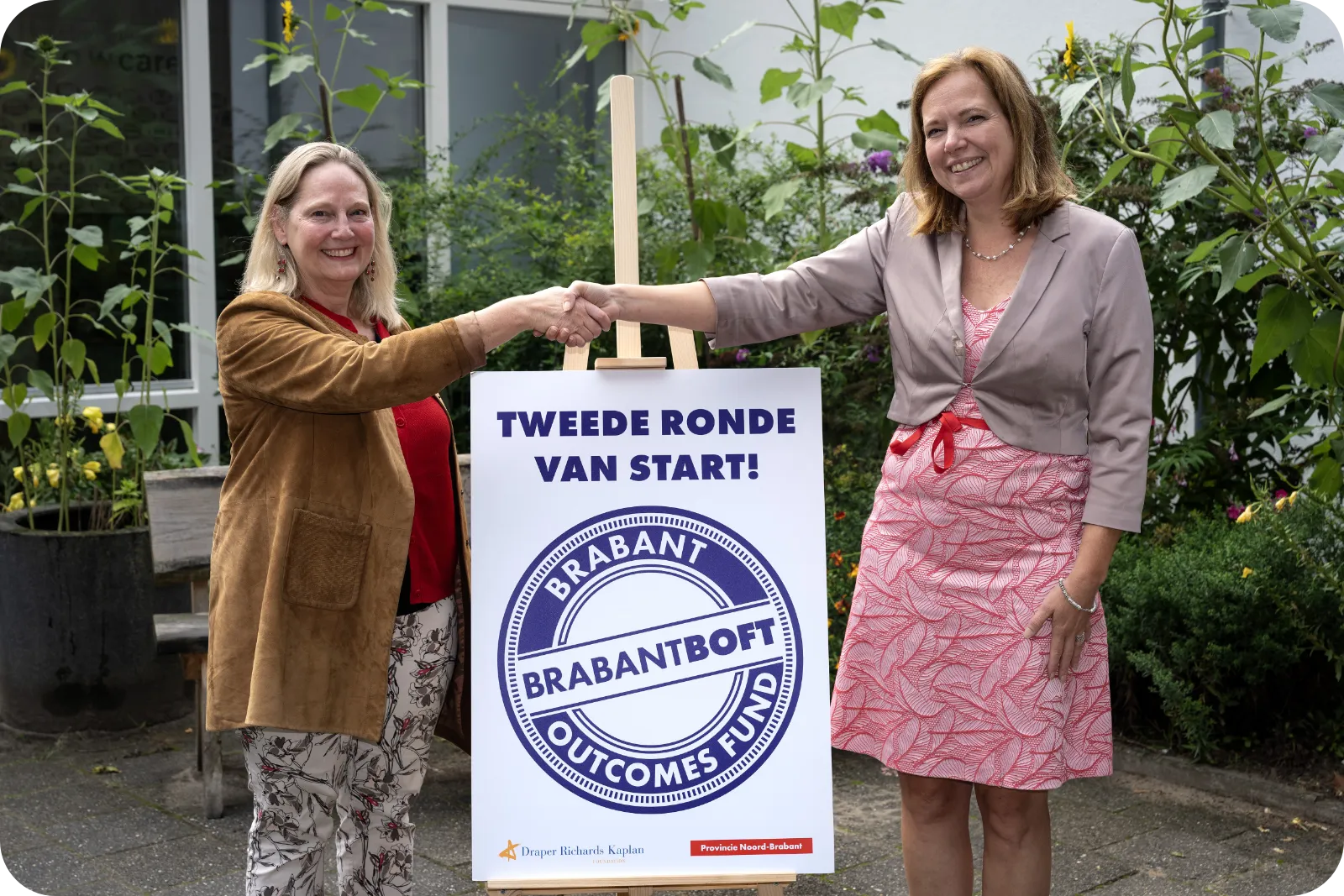 Lisa Jordan, CEO van DRK en Saskia Boelema, gedeputeerde Brede Welvaart, schudden elkaar de hand op de aftrap van de tweede ronde van Brabant Outcomes Fund.