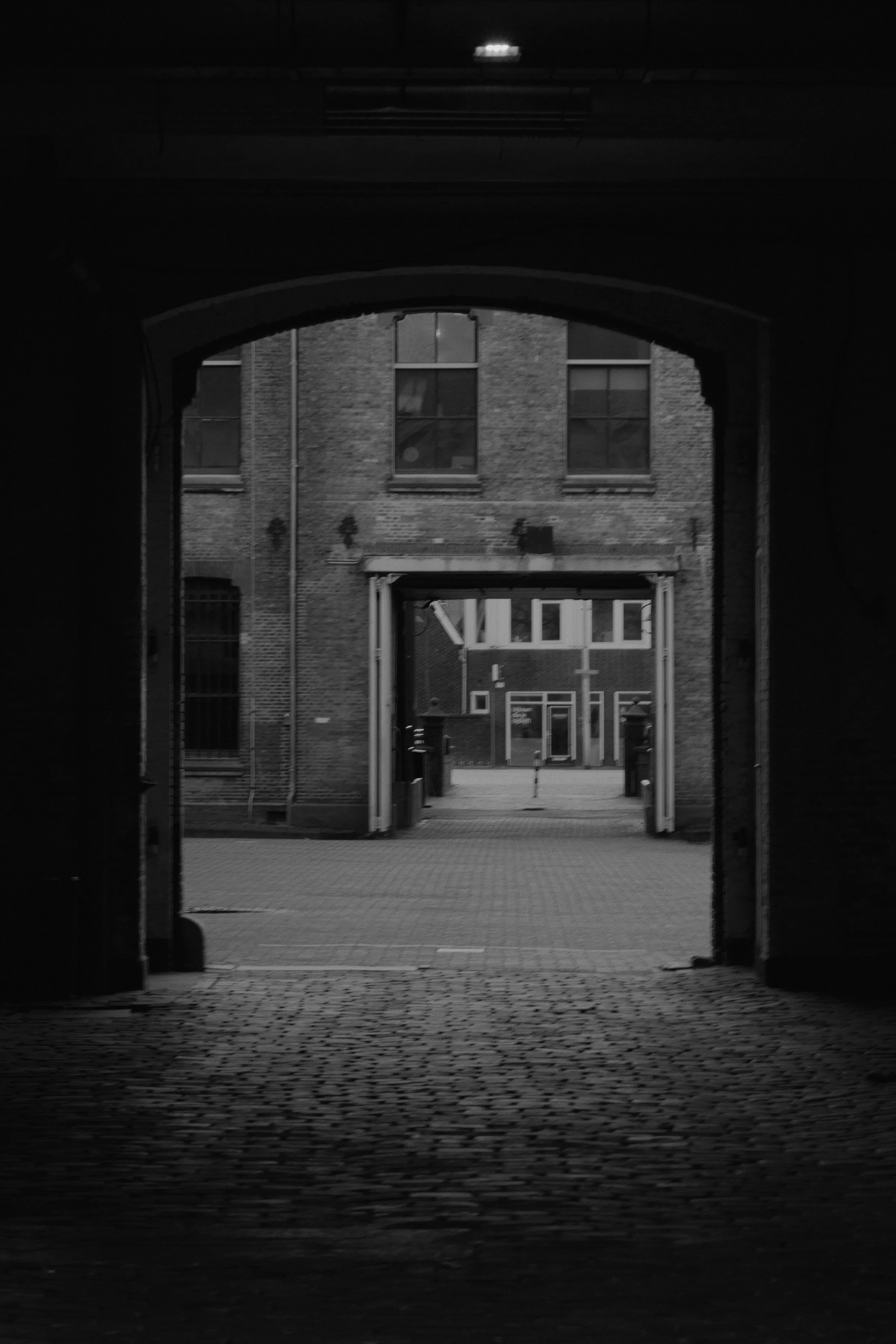 Een winkelstraat, ingekaderd door een poortje aan het einde van een tunnel.